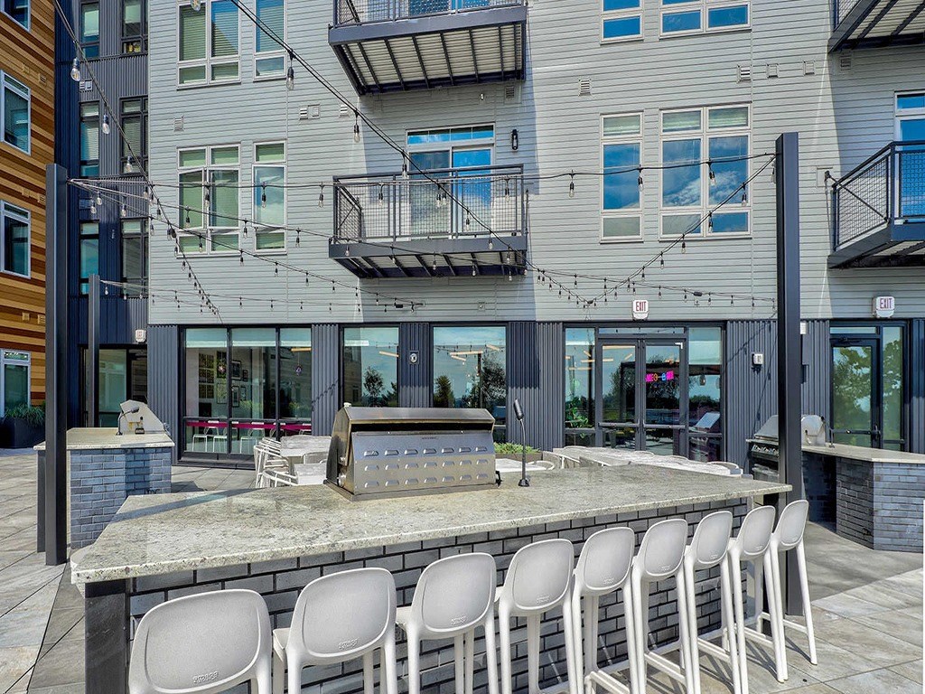 a bar with chairs and a grill in front of a building
